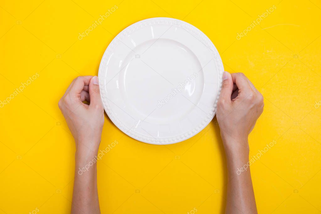woman two hands hold a white dish on yellow background
