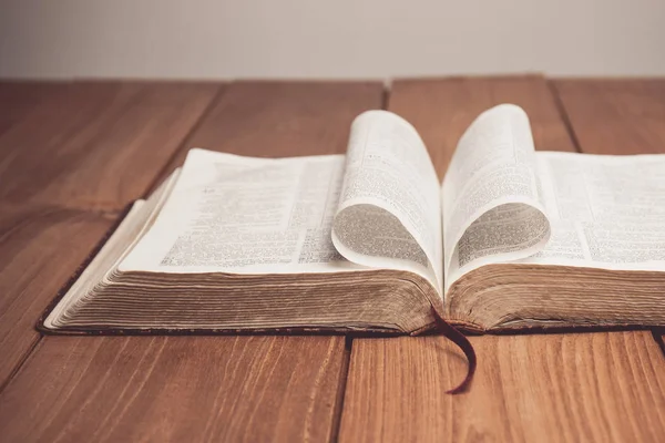 Винтажный тон Библии на столе со сложенными в форме сердца страницами — стоковое фото