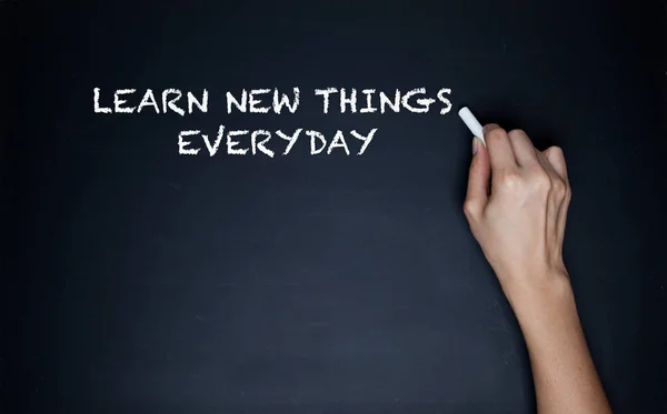 The human hand starts writing with chalk on a clean blackboard