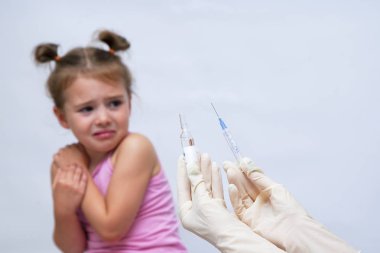 Doktor ağlayan kıza aşı enjeksiyonu yapıyor