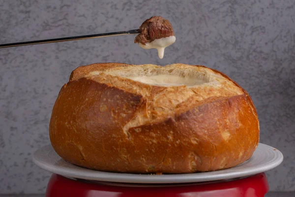 Delicious cheese fondue served inside the bread. close up of meat ready to dip in chees