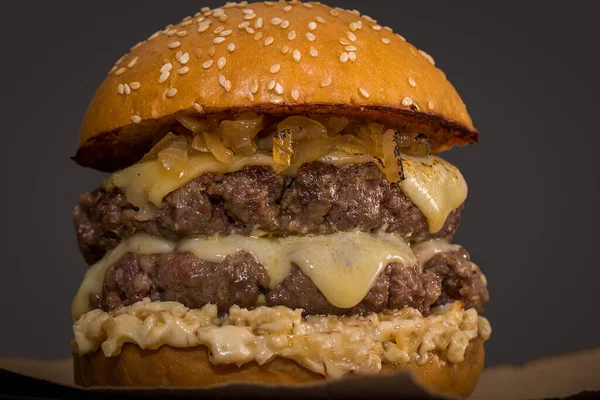 Dubbele Cheeseburger Met Saus Gekarameliseerde Bruin Papier Grijze Achtergrond — Stockfoto