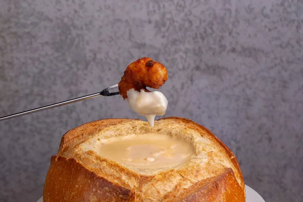 Delicious cheese fondue served inside the bread. close up of shrimp ready to dip in cheese