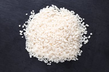 Koyu arkaplanda bir avuç pişmemiş beyaz pirinç. Üst görünüm.
