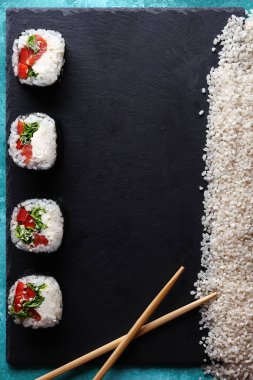 Lezzetli suşi servis tahtasının üzerinde, ahşap sopaların yanında ve pişmemiş, beyaz pirinç, üst manzara. Japon yemeği..