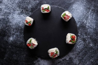 Suşi servis masasında yuvarlak yuvarlanır. Üst manzara, çerçeve. Mesaj için yer. Karanlık arka plan. Japon yemeği..