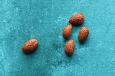 Turkuaz zemin üzerinde bademlerin renkli fotoğrafı, üst görünüm