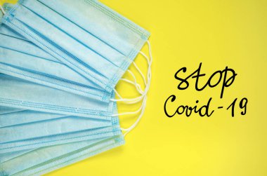 Covid-19 'u durdurun. Sarı arka planda tıbbi maske. Coronavirus koruması ve sağlık hizmetleri. Küresel karantina ve sosyal uzaklık.