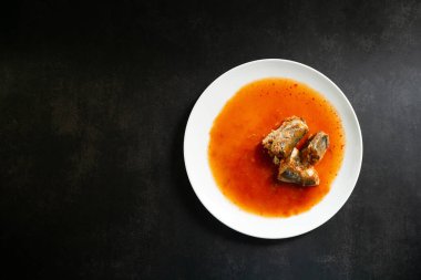 Siyah arka planda domates soslu konserve balık, sardalya, uskumru, Tayland fast food ve üst manzara.