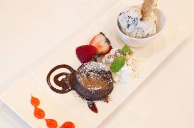 Çikolata ve dondurma beyaz bir kap üzerinde çilek Tatlı aperatifler ile süslenmiş.