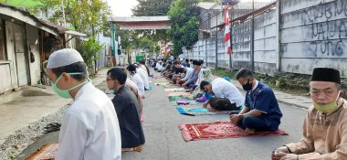 Korona virüsü salgını sırasında yolda dua eden Müslüman erkekler sosyal mesafenin kurallarına uyuyorlar.