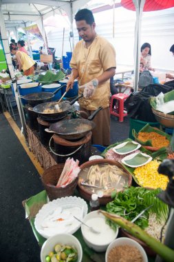 Tay erkek Şef bir noodle domates ve geleneksel şekilde woking havuç ile hazırlama tava üzerinde Tay yastık bir pişirme. 