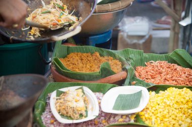 Tay erkek Şef bir noodle domates ve geleneksel şekilde woking havuç ile hazırlama tava üzerinde Tay yastık bir pişirme. 