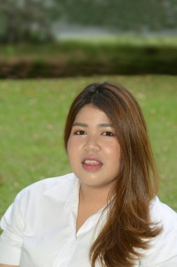 Güzel gülen yüz Asyalı şişman kadın poz mutluluk parkta bir sandalyeye portresi.