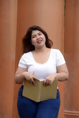 Asyalı güzel gülen yüzü şişman kadın portresi ayakta poz ve kutup Park Grup üzerinde bir kitapçık tutun.