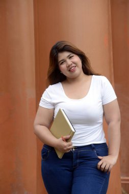 Asyalı güzel gülen yüzü şişman kadın portresi ayakta poz ve kutup Park Grup üzerinde bir kitapçık tutun. 