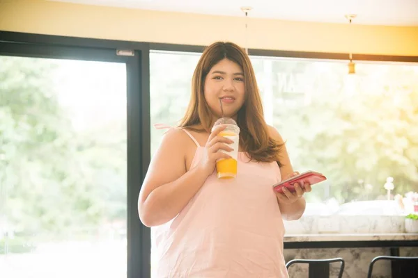 Portrét Docela Asijské Tlustá Žena Pít Pomerančový Džus Používá Mobilní — Stock fotografie