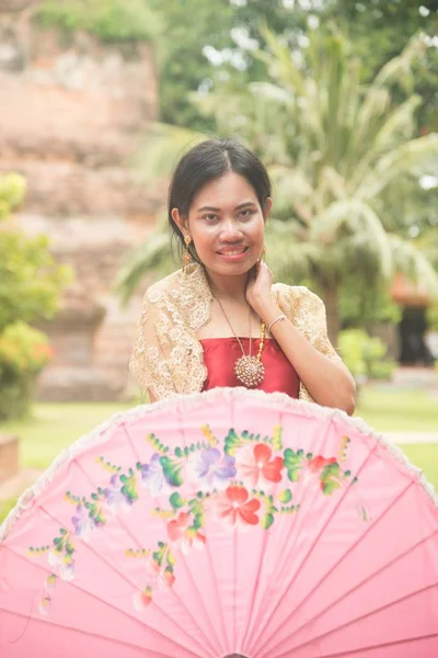 伝統的なドレスでアジアの女性の肖像画をもたらす古代タイの寺院で保持傘 — ストック写真