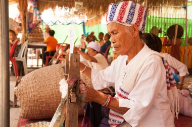 Phayao, Tayland-Mayıs 9,2015: Tanımlanamayan Tai Lue azınlık kadın kıdemli bir iplik geleneksel pamuk ipliği izleri Festivali şaşırtıcı 8 etnik gösterilen ahşap yapılmış antik haddeleme makine tarafından olduğunu.