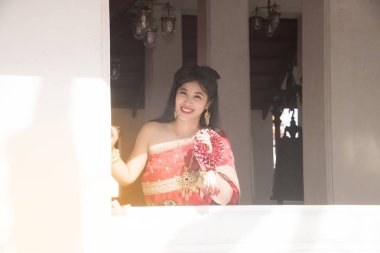 Orta Tayland klasik geleneksel elbise takım ayakta tutun garland oldukça Taylandlı kadın kapalı bir Tay tapınak inşa kutbunda yakınındaki poz.