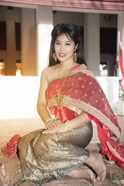 中央タイの古典的な伝統的なドレス スーツ座りでかなりタイの女性 タイの寺院の背景でポーズをとってください — ストック写真