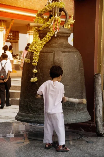 Um menino batendo grande sino ao ar livre no topo da colina em Wat Sangkas Ratanakhiri templo . — Fotografia de Stock