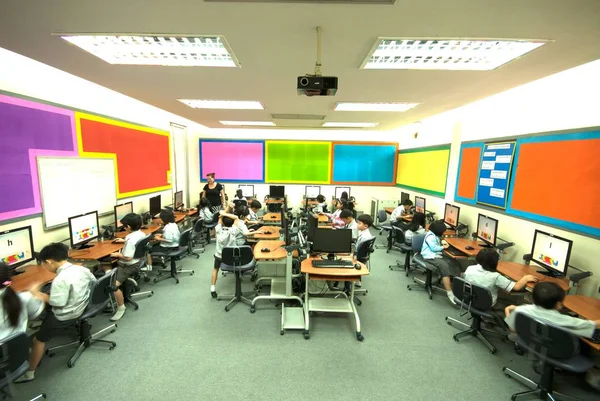 Азиатский ребенок учится пользоваться компьютером в начальной школе в классе . — стоковое фото