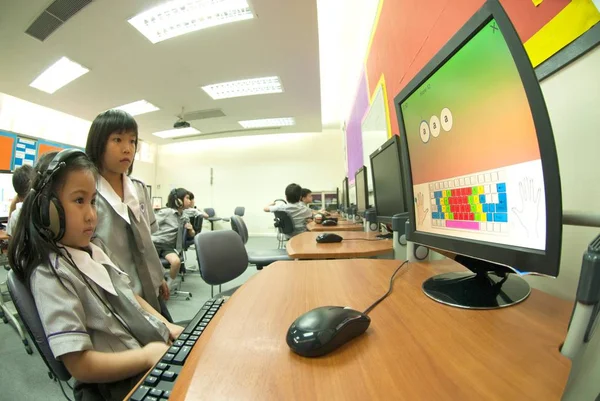 Asiatisches Kind lernt, Computer in der Grundschule im Klassenzimmer zu benutzen. — Stockfoto
