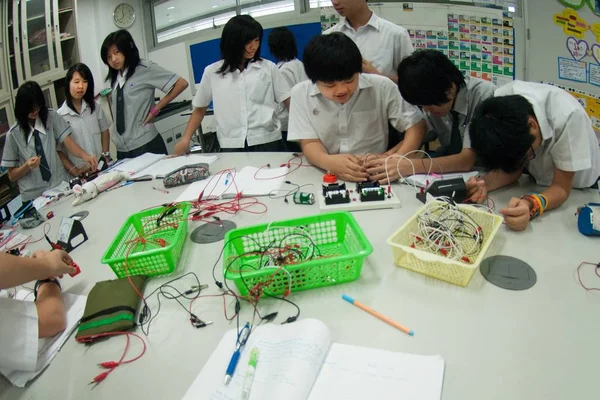 Gruppe asiatischer Grundschüler lernt im Klassenzimmer über Elektrizität. — Stockfoto