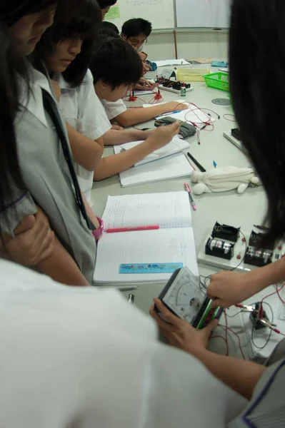 Gruppe asiatischer Grundschüler lernt im Klassenzimmer über Elektrizität. — Stockfoto