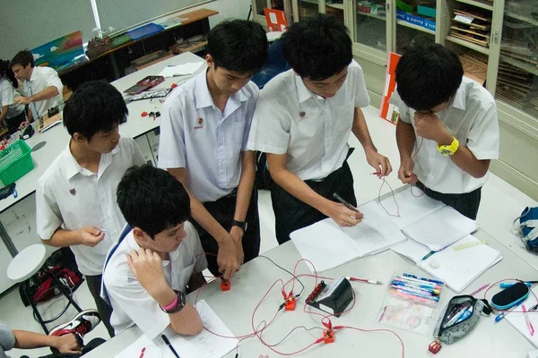 Група азіатських початкових студентів вивчають про електроенергію в класі. — стокове фото