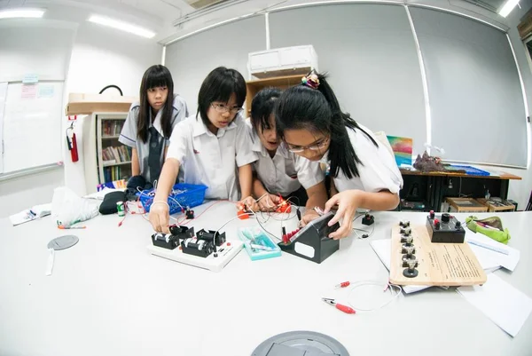 Gruppe asiatischer Grundschüler lernt im Klassenzimmer über Elektrizität. — Stockfoto