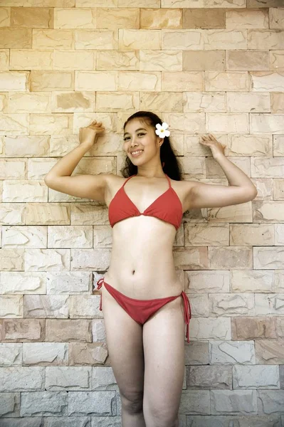 Retrato de mujer asiática bonita en bikini rojo sexy posando y de pie frente a la pared . — Foto de Stock