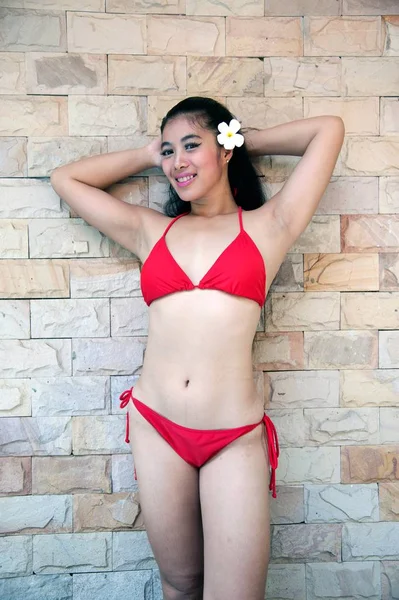 Портрет красивой азиатки в сексуальном красном бикини, позирующей и стоящей на стене . — стоковое фото