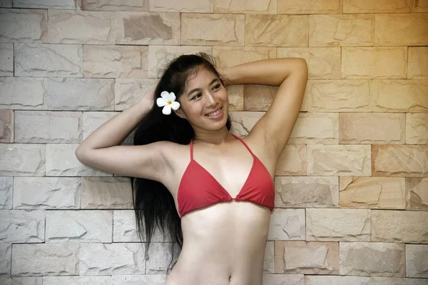 Seksi kırmızı bikini poz ve duvarda ön ayakta güzel Asyalı kadın Portresi. — Stok fotoğraf