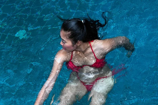 Hezká asijská žena s červenými bikiny plavání v bazénu. — Stock fotografie