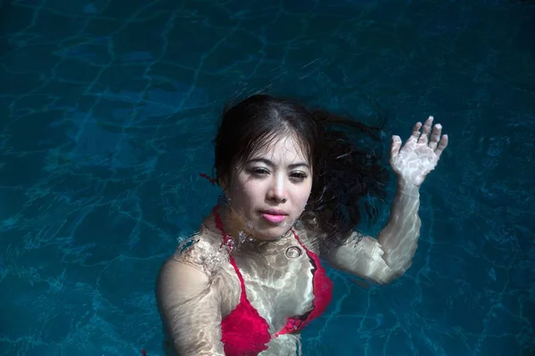 Ładna Azjatycka kobieta ubrana w czerwone bikini pływanie na basenie. — Zdjęcie stockowe