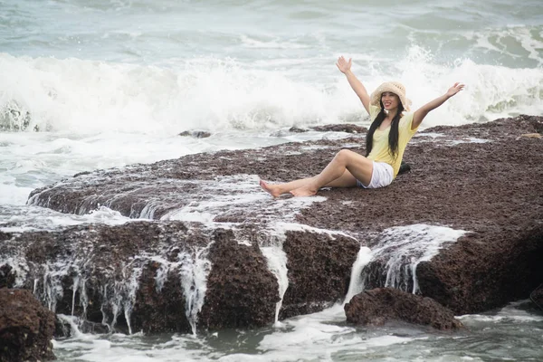 Asijská hezká samice sedící na skalách s silnou vlnou a relaxačním štěstím. — Stock fotografie