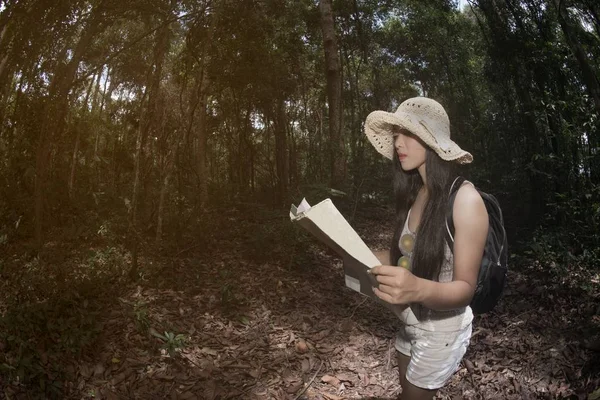 Jolie femme asiatique à la recherche d'une carte dans la forêt . — Photo