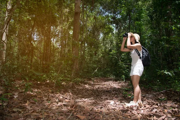 Jolie femme asiatique regardant à travers les jumelles un bonheur dans la forêt . — Photo