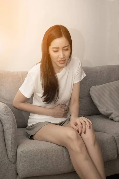 A menina segura o estômago com as duas mãos. Estômago perturbado ou dor durante a menstruação . — Fotografia de Stock