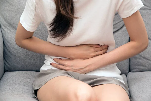 La chica sostiene su estómago con ambas manos. Malestar estomacal o dolor durante la menstruación . —  Fotos de Stock