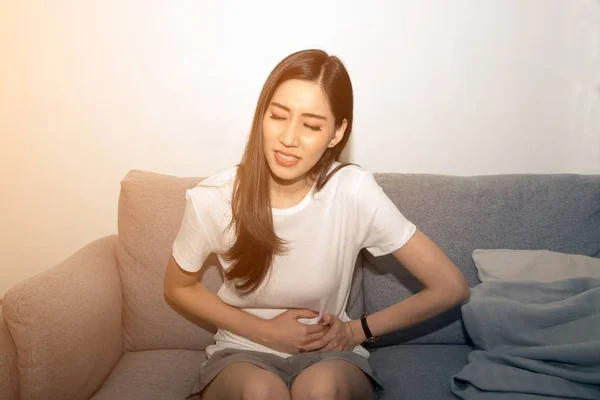 A menina segura o estômago com as duas mãos. Estômago perturbado ou dor durante a menstruação . — Fotografia de Stock
