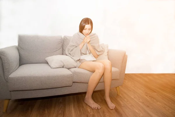 Азіатські жінки сумно страждає від холоду через лихоманку на дивані в кімнаті. — стокове фото