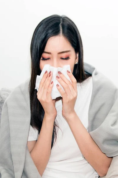 Ázsiai nők hangsúlyozzák, hogy szenvednek az allergiában, és csukd be az orrát a selyempapír. Mivel a tüsszgő egész idő alatt. — Stock Fotó