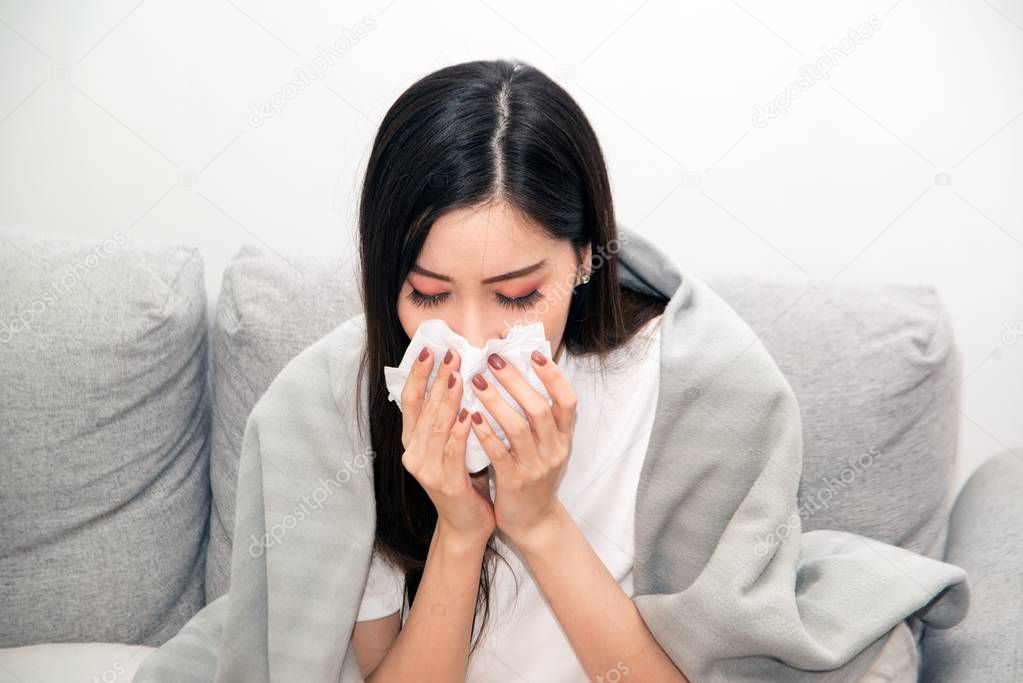 Asian women with stress that suffer from allergies and close the nose with tissue paper. Because of having sneezing all the time.