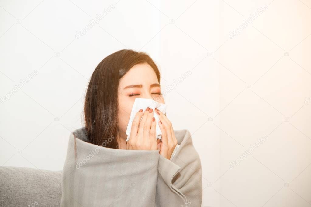 Asian women with stress that suffer from allergies and close the nose with tissue paper. Because of having sneezing all the time.