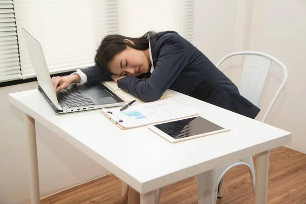 Jovem mulher de negócios asiática deitada na mesa no escritório porque cansado sobrecarregado . — Fotografia de Stock