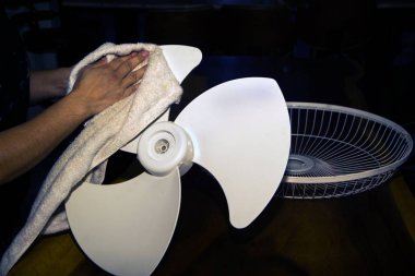 Housekeeper use white cloth Wipe and clean the electric fan. clipart