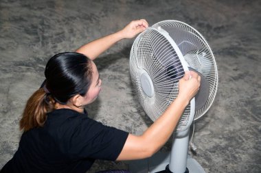 Temizlikçi, temizlik ten sonra bir elektrik vantilatası monte ediyor ve kuruyor..